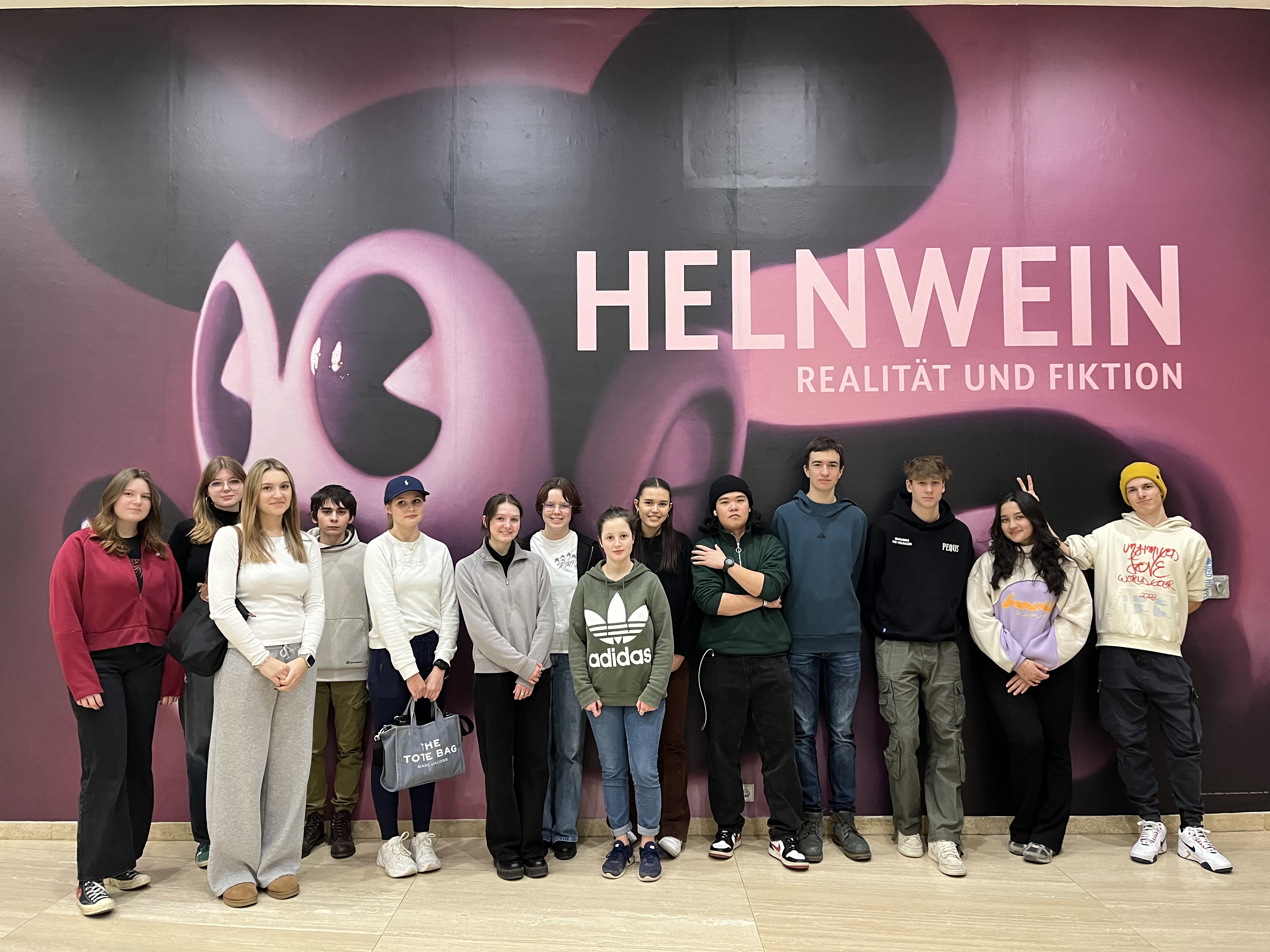 Eine Gruppe von Schülerinnen steht vor dem Plakat zur Ausstellung von Gottfried Helnwein, das eine aggressive Mickeymaus zeigt