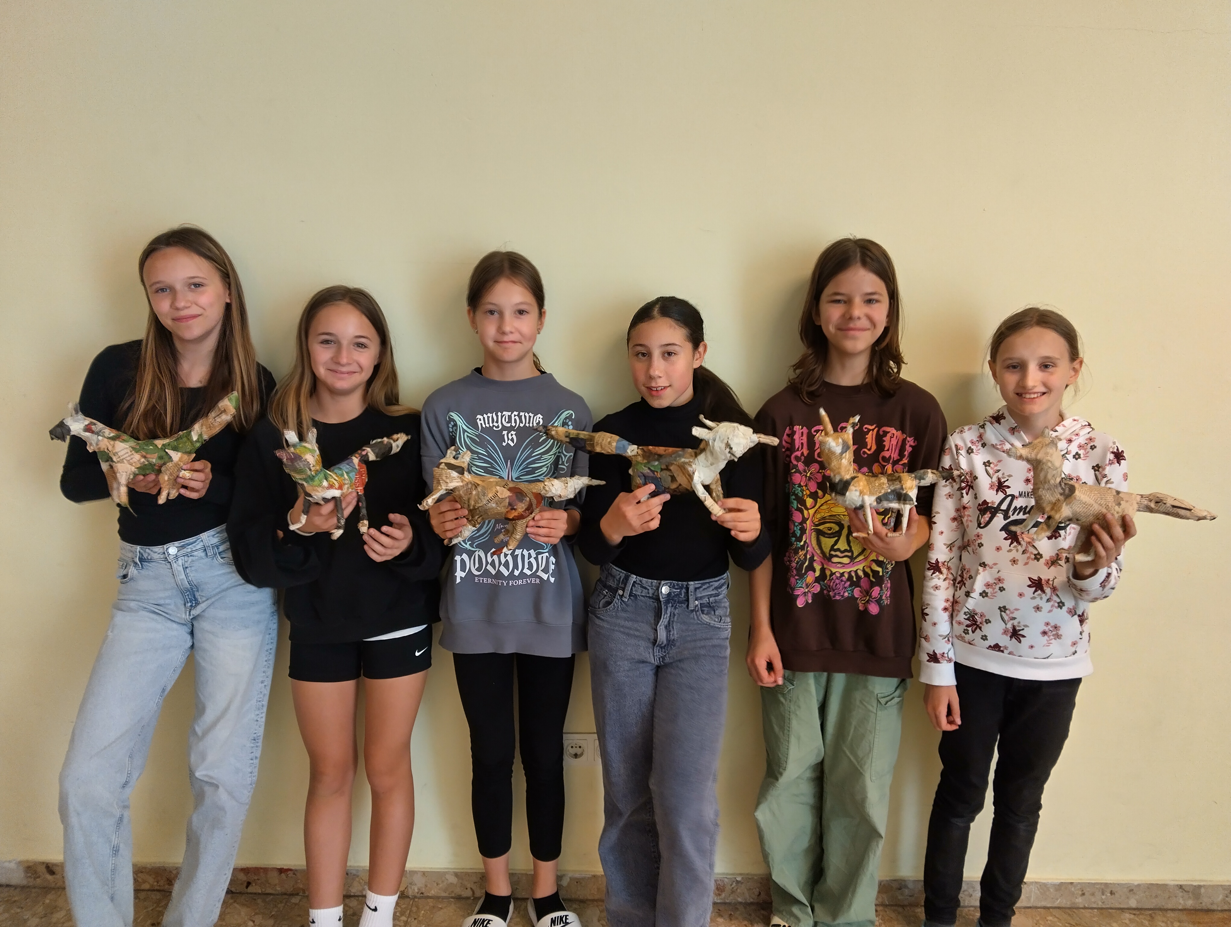 Schülerinnen präsentieren stolz ihre Tierplastiken aus Kleister und Zeitung