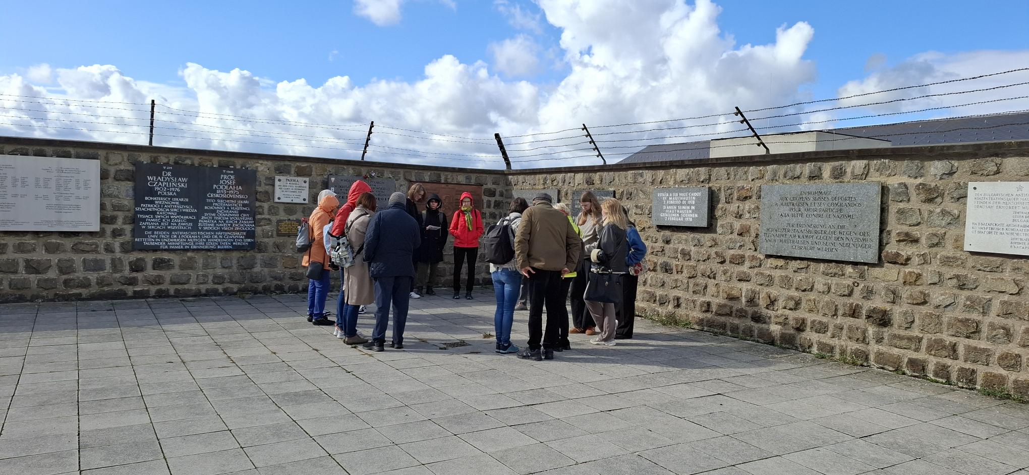 Eine Gruppe Menschen steht vor der Klagemauer im KZ Mauthausen 